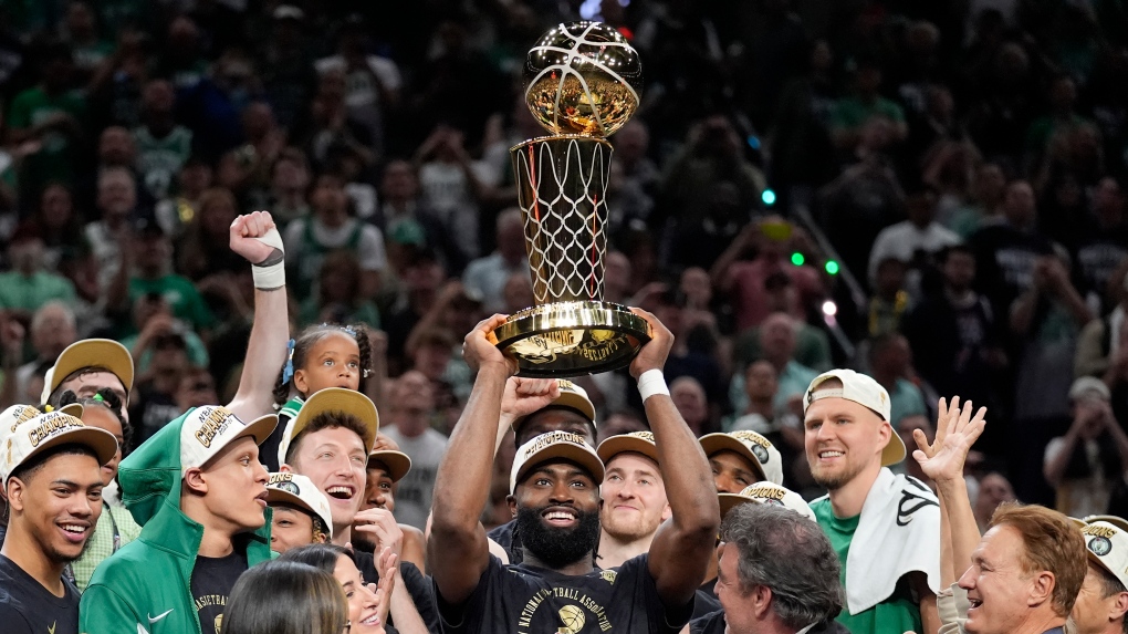 Boston Celtics guard Jaylen Brown, center, holds up the Larry O'Brien Championship Trophy as he celebrates with the team after they won the NBA basketball championship with a Game 5 victory over the Dallas Mavericks, Monday, June 17, 2024, in Boston. (AP Photo/Charles Krupa)