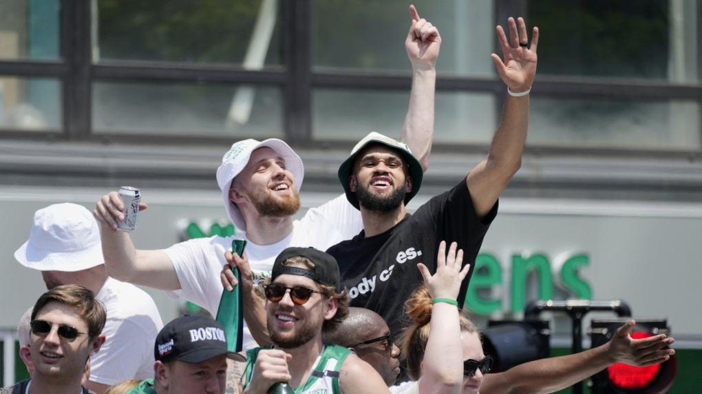 Boston Celtics' Derrick White, right, celebrates the team's NBA basketball championship during a duck boat parade Friday, June 21, 2024, in Boston. (AP Photo/Michael Dwyer)