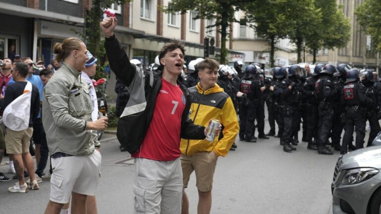 England soccer fans cheer in front of police ahead the Group C match between Serbia and England at the Euro 2024 soccer tournament in Gelsenkirchen, Germany, Sunday, June 16, 2024. (AP Photo/Markus Schreiber)