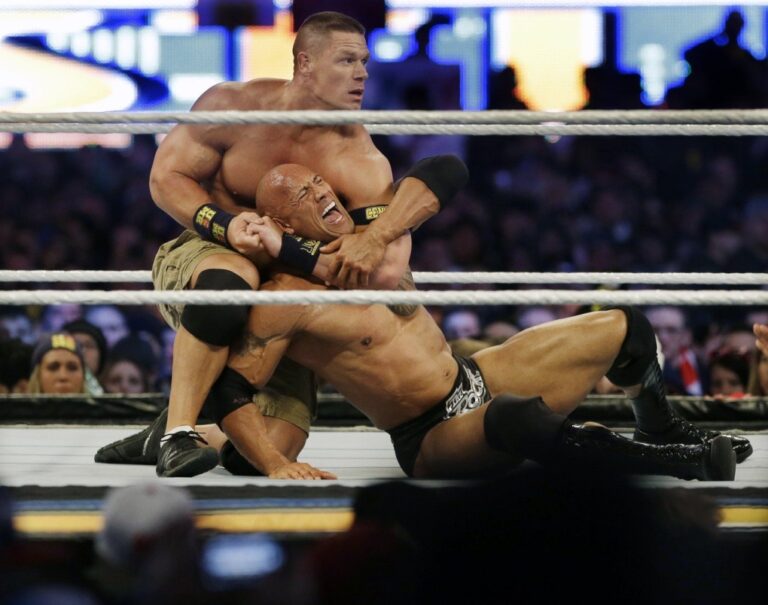 Wrestler John Cena, top, chokes Dwayne Douglas Johnson, known as The Rock, as they wrestle, April 7, 2013, in East Rutherford, N.J., during Wrestlemania. Cena announced Saturday, July 6, 2024, that he will retire from professional wresting next year after two decades in the ring. (AP Photo/Mel Evans, File)