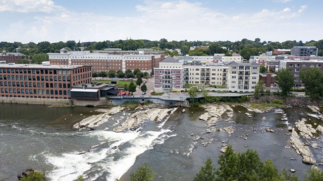 Une vue aérienne des chutes Winooski, avec de l'eau se précipitant sur des rochers et plusieurs grands bâtiments en arrière-plan.
