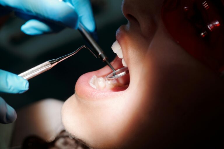 A dental professional examines the inside of a patient's mouth. (Pexels)