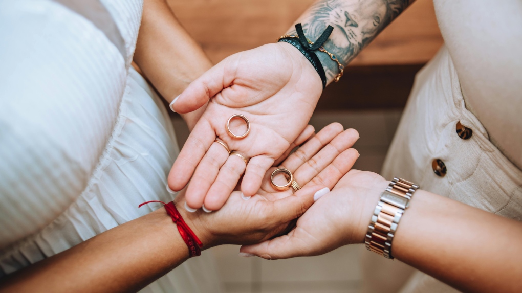 Two people hold wedding rings during a wedding ceremony. (Pexels)