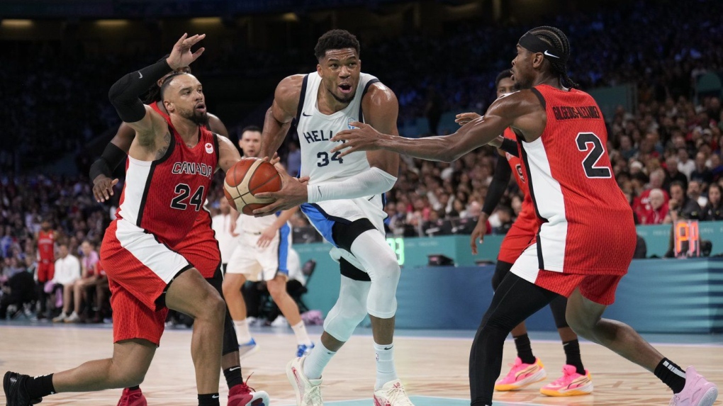 Giannis Antetokounmpo, of Greece, drives between Dillon Brooks, left, and Shai Gilgeous-Alexander, of Canada, in a men's basketball game at the 2024 Summer Olympics, Saturday, July 27, 2024 in Villeneuve-d'Ascq, France. (Mark J. Terrill/AP Photo)