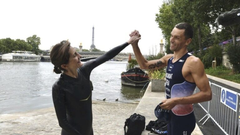 France's Minister of Sports and the Olympic and Paralympic Games Amelie Oudea-Castera, left and Tokyo 2020 Paralympics Triathlon gold medalist Alexis Hanquinquant gesture ahead of swimming in the River Seine, in Paris, Saturday, July 13, 2024.  (Ministry Of Sport, Olympic And Paraolympic Games via AP)