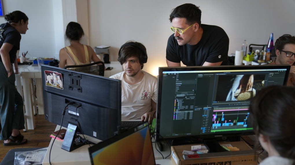 Chris Langer, top right, co-founder of CMYK, a digital design agency, speaks with an staff member at their office in New York, Tuesday, June 25, 2024. Last year, Langer started hearing chatter about the four-day work week, so he decided to try it out during the summer. (AP Photo/Seth Wenig)