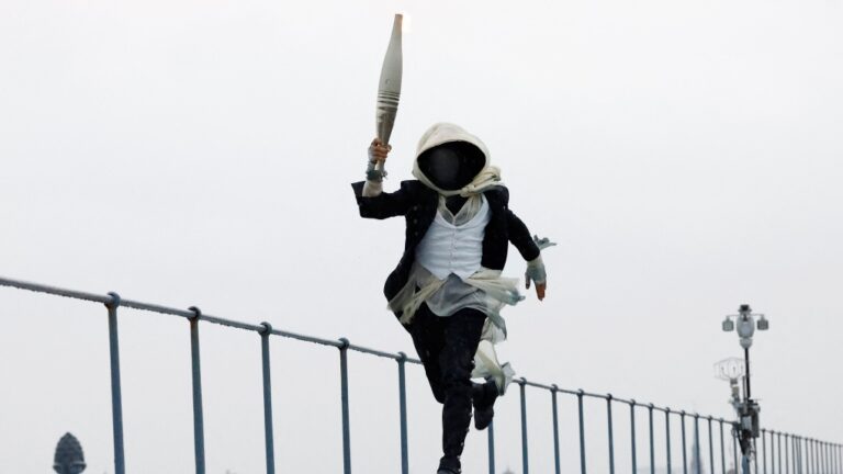 A torch bearer runs atop the Musee d'Orsay, in Paris, France, during the opening ceremony of the 2024 Summer Olympics, Friday, July 26, 2024. (Peter Cziborra/Pool Photo via AP)