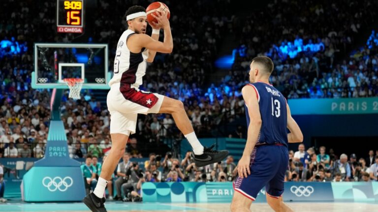 United States' Devin Booker (15) grabs a rebound over Ognjen Dobric (13), of Serbia during a men's semifinals basketball game at Bercy Arena at the 2024 Summer Olympics, Thursday, Aug. 8, 2024, in Paris, France. (Mark J. Terrill / AP Photo)