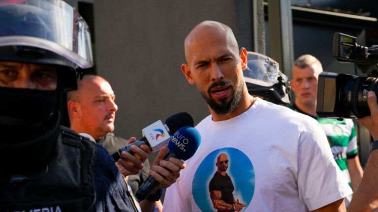 Andrew Tate talks to media as he is being led for questioning after a police search raid on his residence, on the outskirts of Bucharest, Romania, Wednesday, Aug. 21 2024. (AP Photo/ Vadim Ghirda)