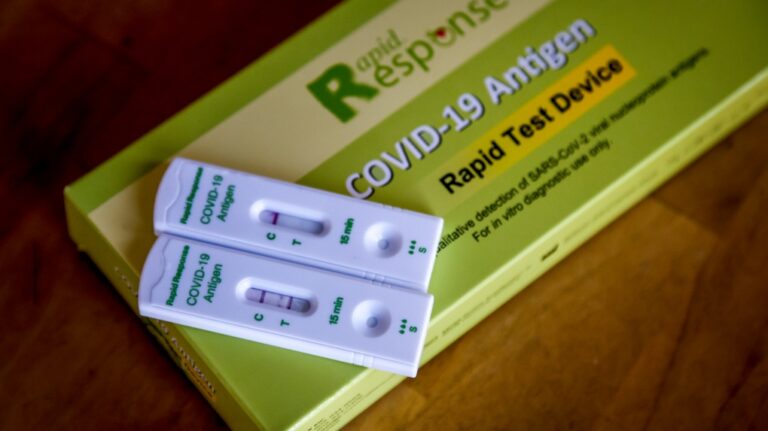 Positive, left, and negative COVID-19 antigen rapid tests are pictured in Calgary on Jan. 4, 2022. (Jeff McIntosh / The Canadian Press)