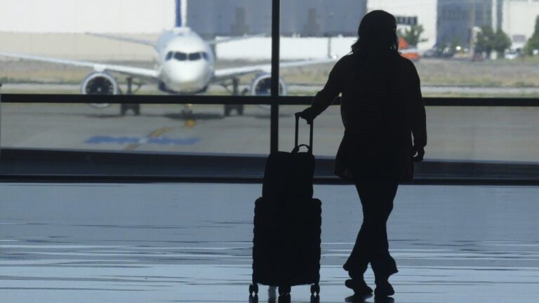 A holiday traveler looks out at a airplane at Salt Lake City International Airport, in Salt Lake City, July 3, 2024. (AP Photo/Rick Bowmer, File)