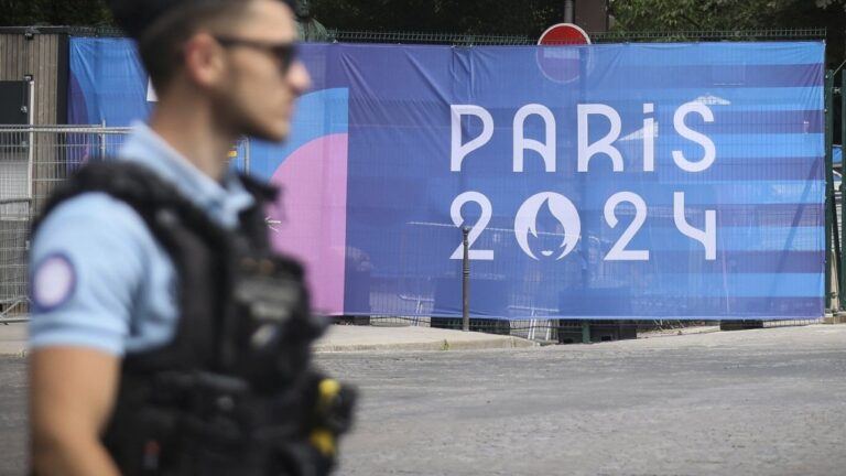 A police officer walks past a Paris Olympics canvas at the 2024 Summer Olympics, Saturday, July 20, 2024, in Paris, France. (AP Photo/Thomas Padilla, File)