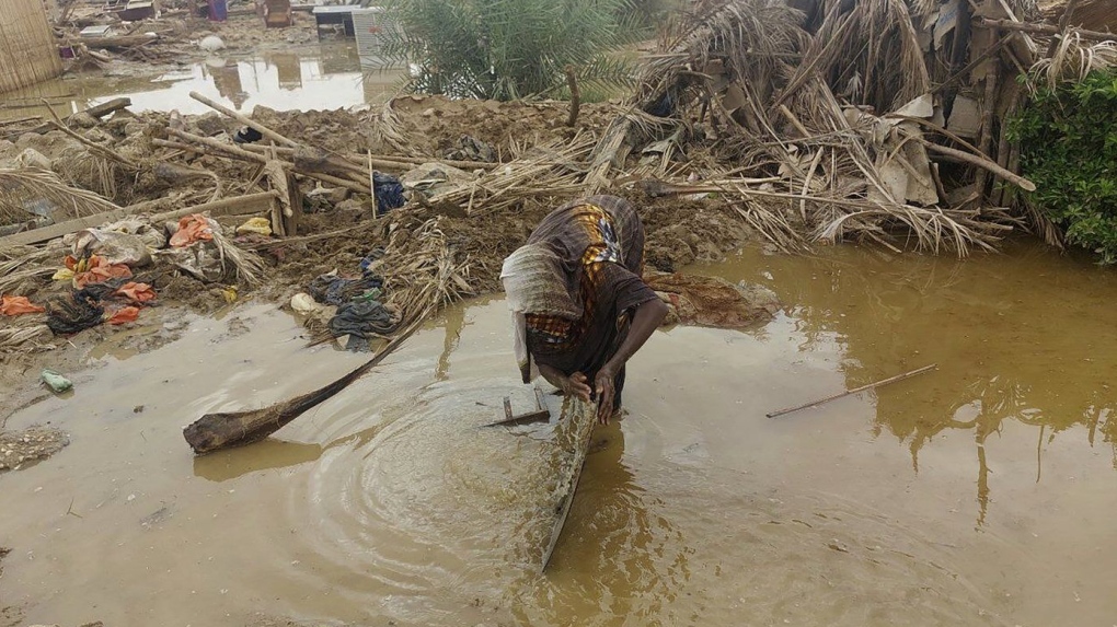 A woman sorts through floodwaters near her damaged home near the city of Abu Hamdan in Northern Sudan on Aug. 7, 2024. (AP Photo/ Samira Hassan)