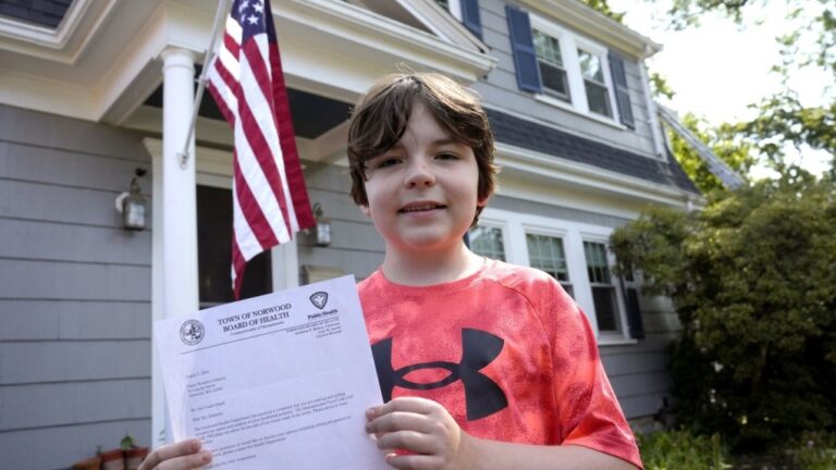 Danny Doherty, 12, of Norwood, Mass., stands for a photograph Wednesday, Aug. 21, 2024, in front of his home in Norwood, while holding a letter from the Town of Norwood Board of Health advising his family that they may not sell homemade ice cream at an ice cream stand near their home. (AP Photo/Steven Senne)