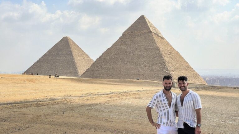 This 2023 photo shows Stefan Arestis, right, and Sebastien Chaneac, at the Pyramids in Egypt. The two are globetrotters who run the LGBTQ2S+-focused travel blog The Nomadic Boys. (The Nomadic Boys via AP)