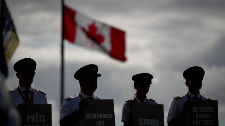 Air Canada pilots air silhouetted while holding signs during an informational picket at Vancouver International Airport in Richmond, B.C., on Tuesday, August 27, 2024. THE CANADIAN PRESS/Darryl Dyck
