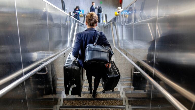 A woman carries her luggage down the stairs at the international airport in Frankfurt, Germany, Tuesday, June 21, 2022. (AP Photo/Michael Probst, File)