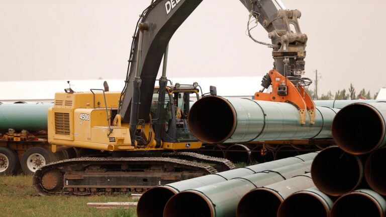 An Enbridge worker loads pipe just west of Morden, Man., Thursday, Aug. 16, 2018. (THE CANADIAN PRESS/John Woods)