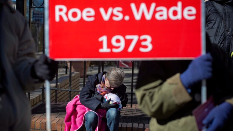Debbie Jung holds her daughter Rose, beneath a sign protesting the 1973 Roe v. Wade Supreme Court decision legalizing abortion, during the March For Life anti-abortion rally outside the State Capitol, Wednesday, Jan. 22, 2014, in Atlanta. (David Goldman / AP Photo)