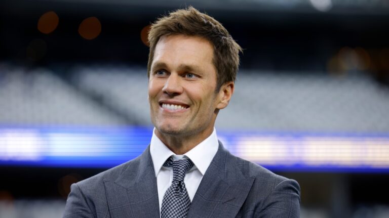 Fox Sports lead NFL analyst Tom Brady stands on the field during warmups before an NFL football game between the Detroit Lions and the Dallas Cowboys in Arlington, Texas, Sunday, Oct. 13, 2024. (AP Photo/Gareth Patterson)