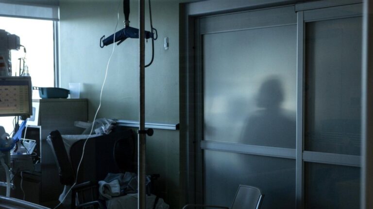 A health-care worker is silhouetted behind a glass panel at a hospital in Sarnia, Ont., on Jan. 25, 2022.THE CANADIAN PRESS/Chris Young
