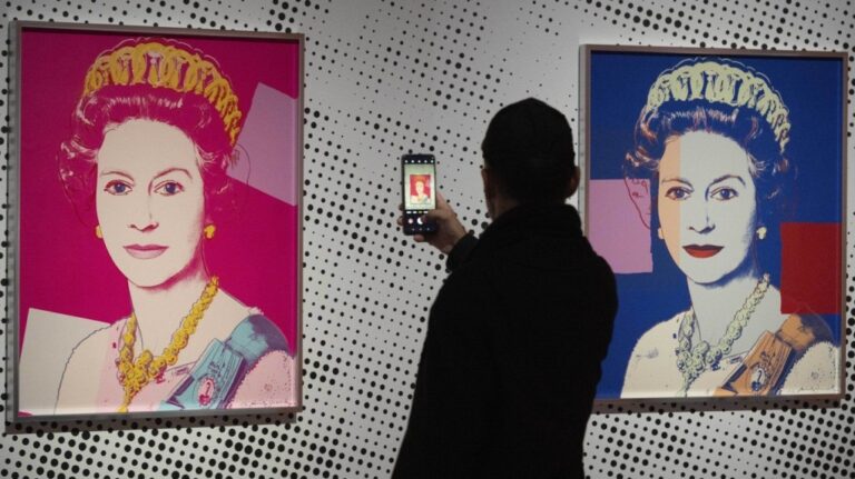 A man takes an image of a screen print depicting Queen Elizabeth II, one in a series of sixteen prints of four queens titled Reigning Queens, 1985, by Andy Warhol at museum Paleis Het Loo in Apeldoorn, Netherlands, Wednesday, Oct. 9, 2024, similar to a Warhol work stolen from a gallery in Oisterwijk, Netherlands, early Friday, Nov. 1, 2024. (AP Photo/Peter Dejong)