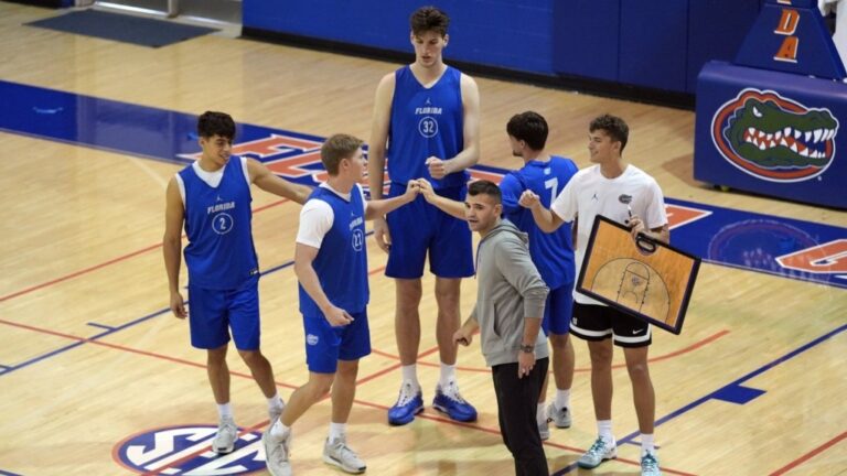 Olivier Rioux, back center, a 7-foot-9 NCAA college basketball player at Florida, gathers with coaches and teammates at the team's practice, Friday, Oct. 18, 2024, in Gainesville, Fla. (AP Photo/John Raoux)