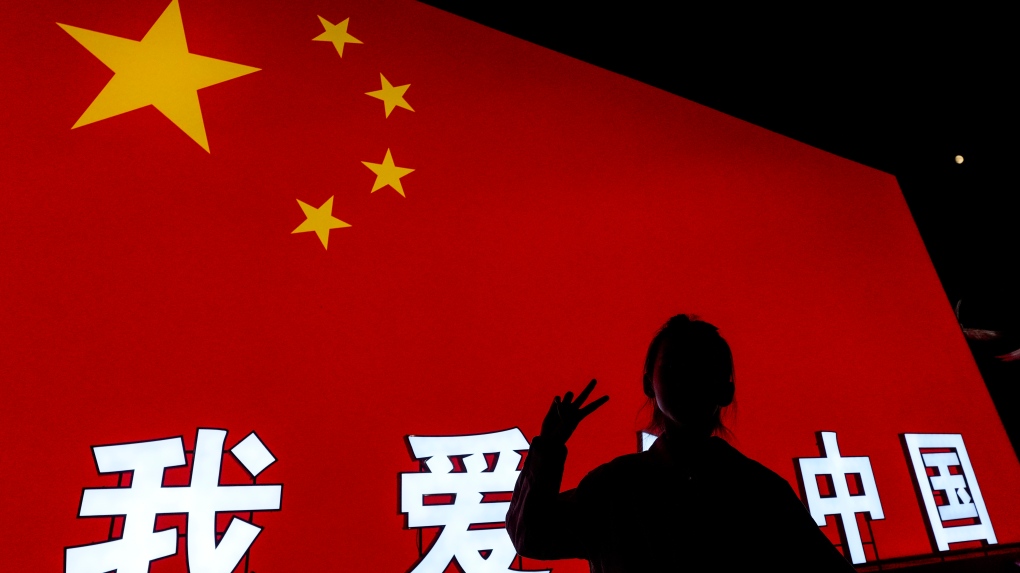 A child poses in front of a Chinese national flag light display baring the words 'I love China' during the grand lantern show at the Garden Expo Park on the eve of Mid-Autumn Festival in Beijing, Sunday, Sept. 15, 2024. (AP Photo/Andy Wong)