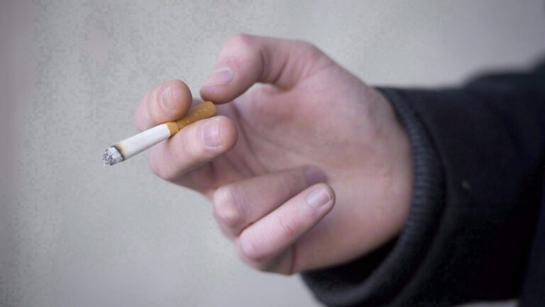 A smoker holds a cigarette outside a building in Vancouver, Monday, Jan. 20, 2014. THE CANADIAN PRESS/Jonathan Hayward