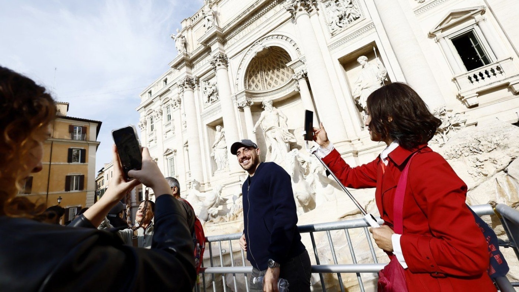 People take selfies on a elevated walkway that gives limited access to the Trevi Fountain monument during maintenance work in Rome, Saturday, Nov. 9, 2024. (Cecilia Fabiano/LaPresse via AP)