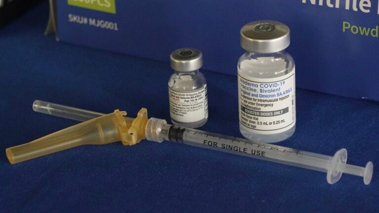 A syringe lies next to vials of COVID-19 booster vaccines at an inoculation station in Jackson, Miss., Friday, Nov. 18, 2022. (AP Photo/Rogelio V. Solis)