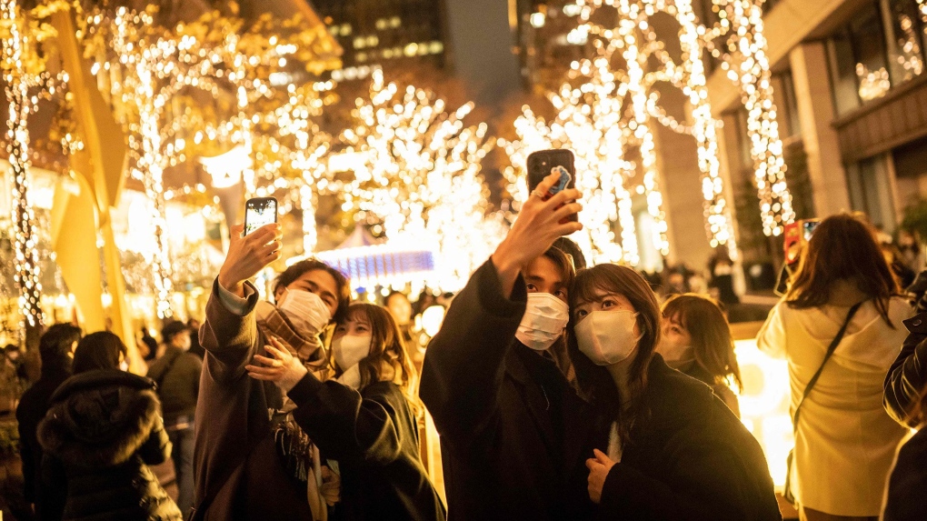 Couples take selfies on a street with Christmas lights in Tokyo on December 25, 2022. (Yuichi Yamazaki/AFP/Getty Images/File via CNN)