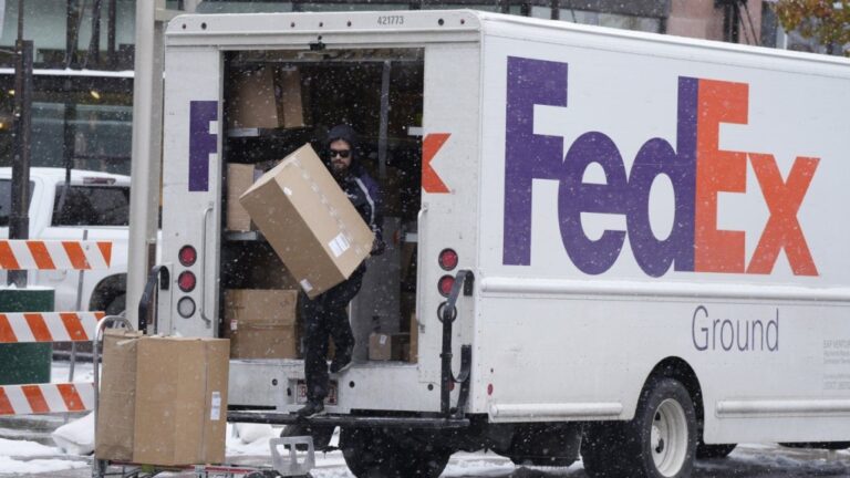 A FedEx delivery person carries a package from a truck on Nov. 17, 2022, in Denver. (AP Photo/David Zalubowski, File)