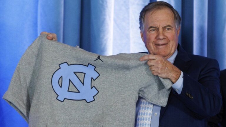 New North Carolina football coach Bill Belichick holds up a UNC branded sleeveless hoodie during his hiring announcement, Dec. 12, 2024, in Chapel Hill, N.C. (AP Photo/Ben McKeown)