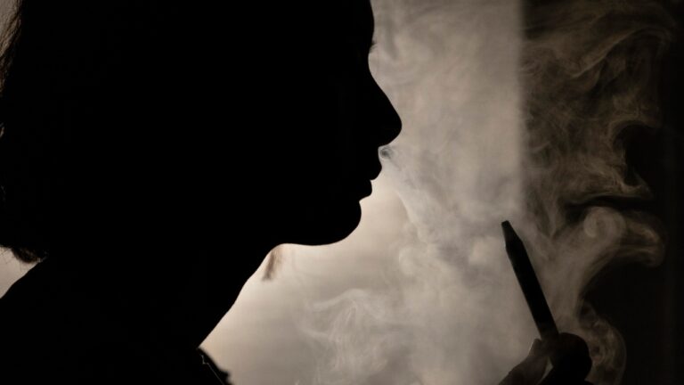 A person poses for a photograph as they vape in Melbourne, March 23, 2023. Recreational vaping will be banned as the government seeks to prevent the next generation of nicotine addicts, Australia's Health Minister Mark Butler said on Tuesday, May 2, 2023.(Diego Fedele/AAP Image via AP)