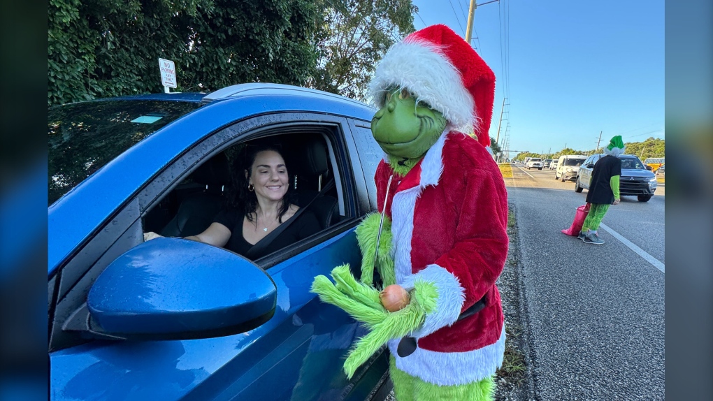 Col. Lou Caputo, dressed as the Grinch, offers an onion to a motorist who was slightly speeding in the Key Largo School zone on Dec. 19, 2024. (Andy Newman / Florida Keys News Bureau / Handout)