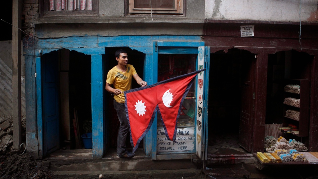 A man carries a Nepalese flag as he stands outside his stall in Kathmandu, Nepal, Wednesday, Sept. 16, 2015. ( (AP Photo/Niranjan Shrestha)