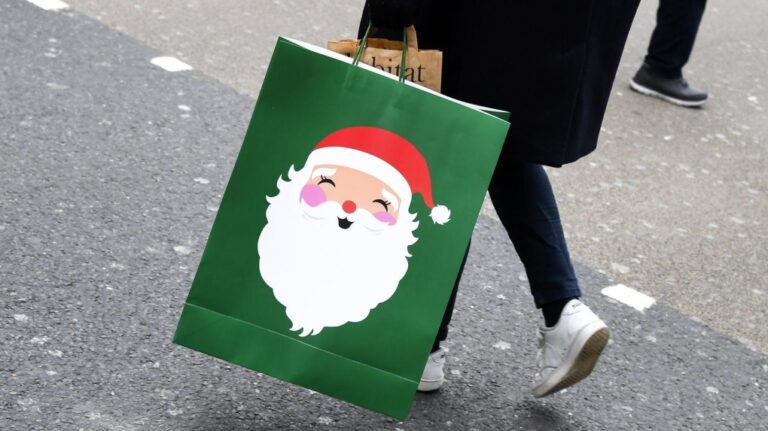 A shopper carries a Christmas-themed bag in London on Dec. 2, 2020. (AP Photo/Alberto Pezzali, File)