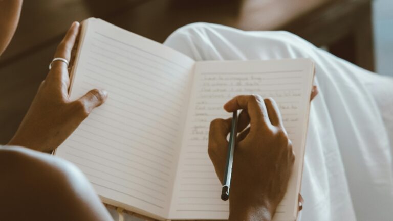 A person writes in a notebook. (Pexels)