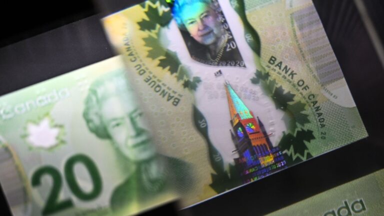A magnifying glass enlarges the holographic image of Parliament Hill's Peace Tower on a $20 bill, shown in a display case at the Bank of Canada Museum in Ottawa, Wednesday, Sept. 4, 2024. THE CANADIAN PRESS/Justin Tang