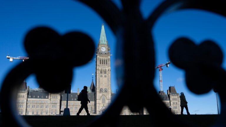 People are silhouetted as buildings cast their shadows in front of the Peace Tower on Parliament Hill, in Ottawa, Nov. 27, 2024. THE CANADIAN PRESS/Adrian Wyld