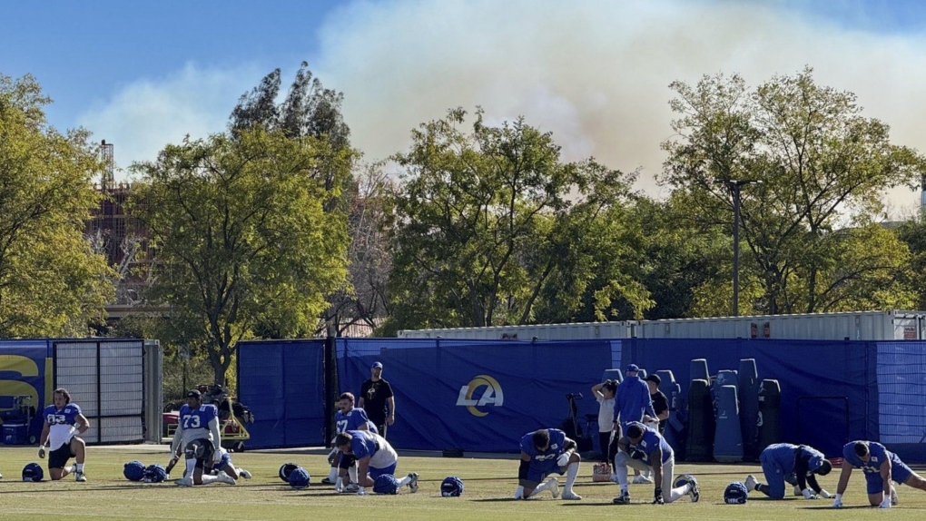 The Los Angeles Rams practice under a plume of smoke from the Palisades Fire in preparation for a playoff game against the Minnesota Vikings on Friday, Jan. 10, 2025. (AP Photo/Dan Greenspan)