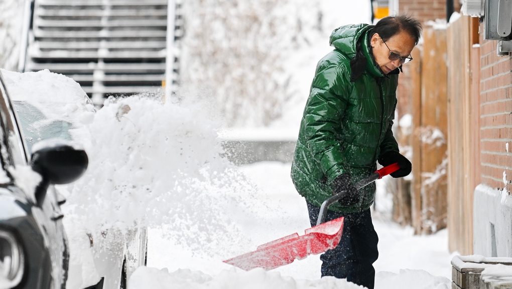 A man clears snow following a snowstorm in Montreal, Tuesday, December 24, 2024. THE CANADIAN PRESS/Graham Hughes